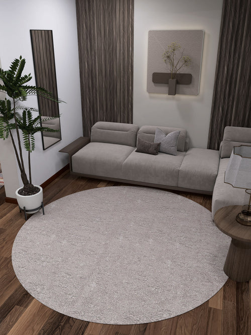 Load image 1 in gallery view. Modern living room with a gray sectional sofa, wood floors, wall art, vertical panels, small side table, mirror, potted plant, and the Slate Charm - Washable Rug - JR1740 (Custom Size) in cream and beige—ideal for high-traffic areas.