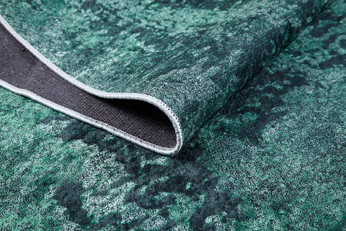 Load image 1 in gallery view. A close-up of the Smokey Mountains - Washable Rug - JR1631 (Custom Size) in green and black, with one corner bent to reveal its dark woven underside and stitched edge.