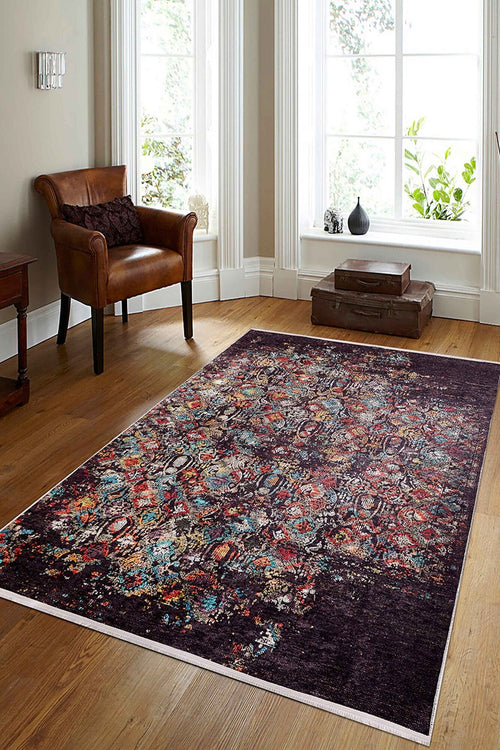 Bild 1 in Galerieansicht laden. A cozy living room with wooden floors, the Soft Haze - Washable Rug - JR1094 (Custom Size) in red, blue, and purple—ideal for high-traffic spaces—a brown leather armchair, small side table, stacked suitcases, and sunlit windows.