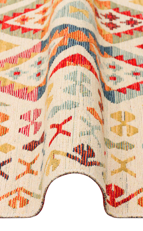 Load image 1 in gallery view. A close-up of the Soft Mosaic - Kilim - NMD08 rug, featuring red, blue, yellow, and green geometric patterns on a cream background. The draped display highlights its texture, thickness, and traditional motifs.
