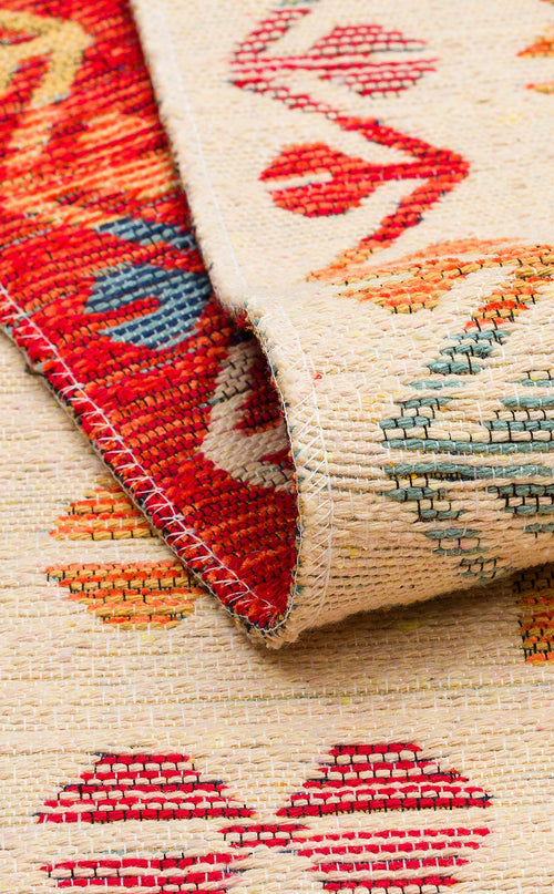 Load image 1 in gallery view. A close-up of the Soft Mosaic - Kilim - NMD08 rug showcases its colorful geometric pattern in red, blue, orange, and beige. One edge is folded over, revealing both the front and back textures along with its traditional motifs.