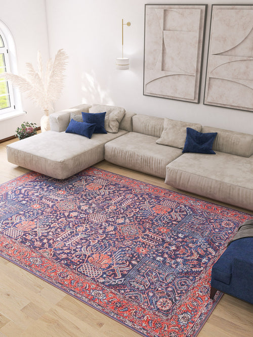 Bild 1 in Galerieansicht laden. A modern living room with a large beige sectional, blue throw pillows, abstract wall art, pampas grass in a vase, and the Solstice Red Navy Washable Rug (LCC3026), ideal for allergy-sensitive homes on light wood flooring.