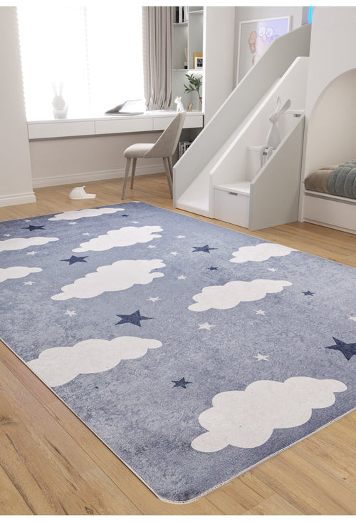 Load image 1 in gallery view. A cozy kids' room features the blue and white "Starry Cloudscape - Machine-Washable Rug JRC045," wooden floors, a window desk with chair, and a small slide to a play area with a rabbit-shaped seat.