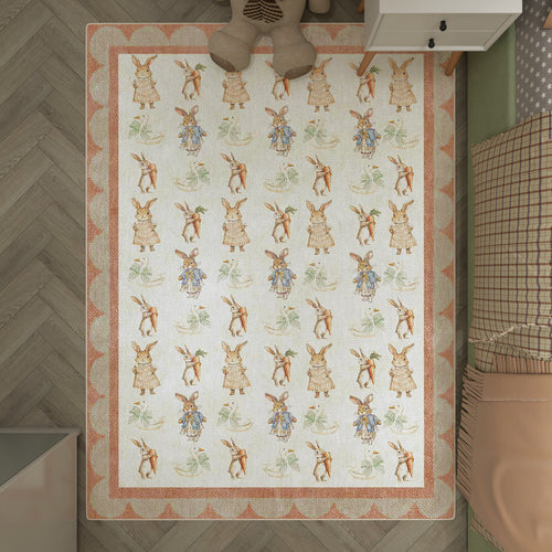 Load image 1 in gallery view. Cream rug with a repeating Peter Rabbit pattern and scalloped peach border, styled in a child's bedroom.
