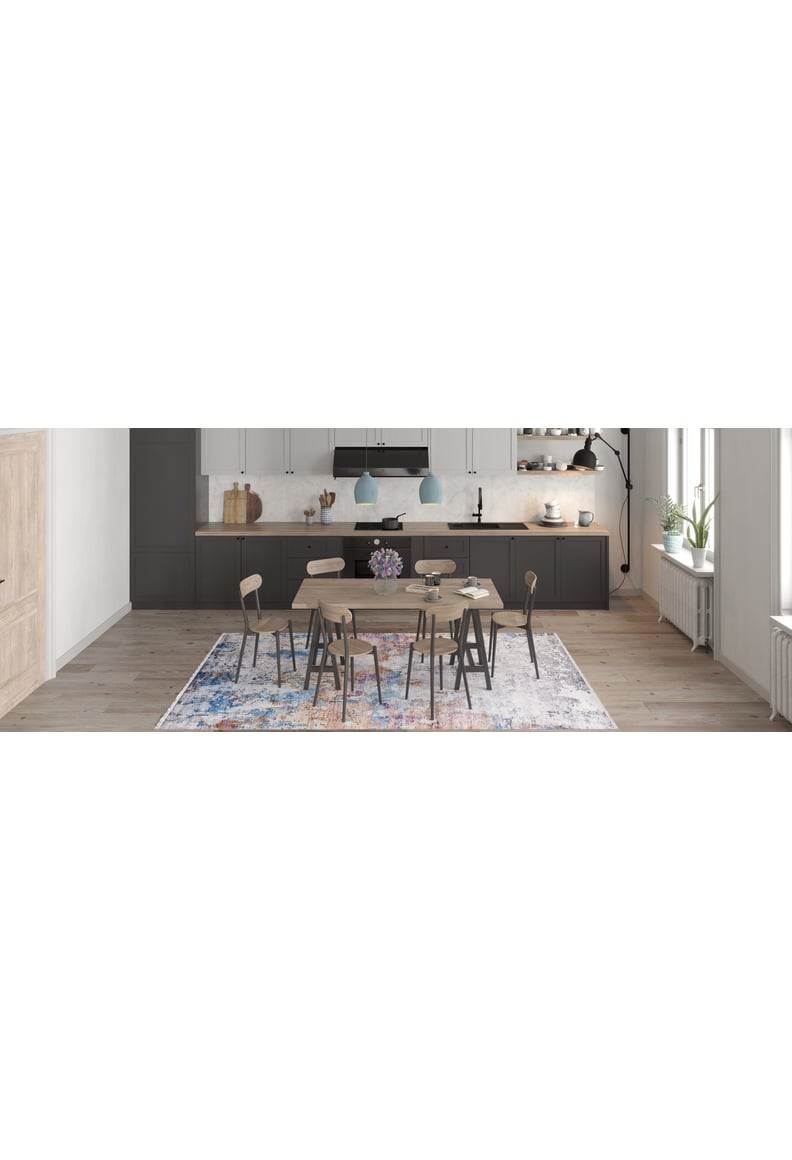 Modern kitchen and dining area with a wooden table, six chairs, pendant lights, dark cabinets, white backsplash, open shelves, and the Striking Statements - Washable Rug - JR786 on light wood flooring. A vase with flowers sits on the table.