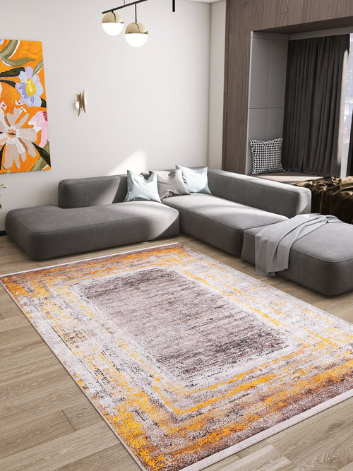 Load image 1 in gallery view. A modern living room features a gray sectional sofa, two light blue pillows, a gray blanket, a colorful abstract painting, and the Subtle Elegance - Washable Rug - JR1174 (Custom Size) in orange, yellow, and white on warm wood flooring.