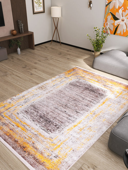 Load image 1 in gallery view. A modern living room with light wood flooring, a gray sofa, plants, floor lamp, colorful floral wall art, and the Subtle Elegance - Washable Rug - JR1174 (Custom Size), a stylish bronze and brown rug perfect for high-traffic areas and easy to clean.