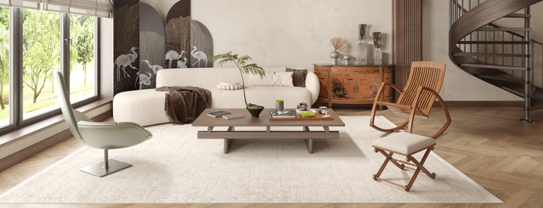 A modern living room features a white sofa, contemporary lounge chair, wooden coffee table, and two wooden chairs atop the Sunset Fade - Washable Rug - JR1878 (Custom Size), with large windows, a spiral staircase, and elegant decor creating a bright, airy space.