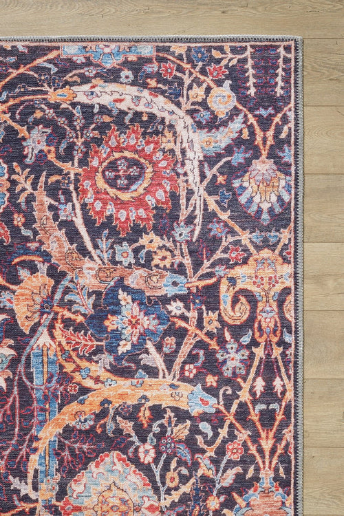 Load image 1 in gallery view. The Sylvanor Colorful Washable Rug - LCC3017, featuring intricate floral and abstract patterns in red, blue, yellow, and cream, is shown with its corner displayed on a light wood floor.
