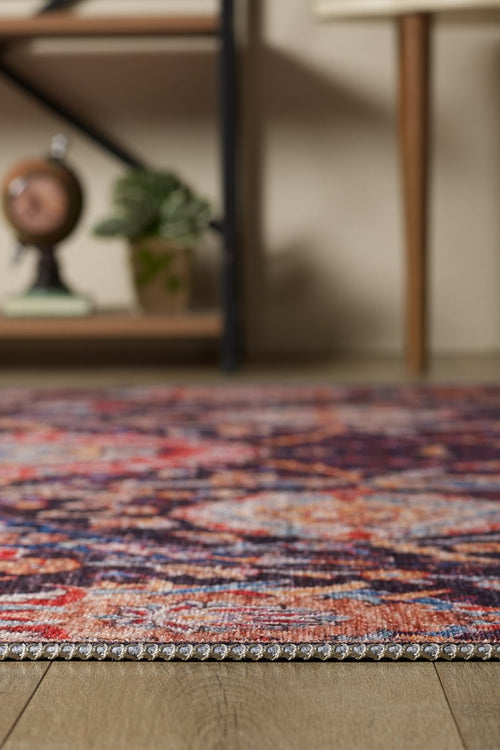 Load image 1 in gallery view. A close-up of the Sylvanor Colorful Washable Rug - LCC3017 on a wooden floor, ideal for high-traffic areas, with a potted plant, decorative clock, and wooden furniture legs in the softly blurred background.