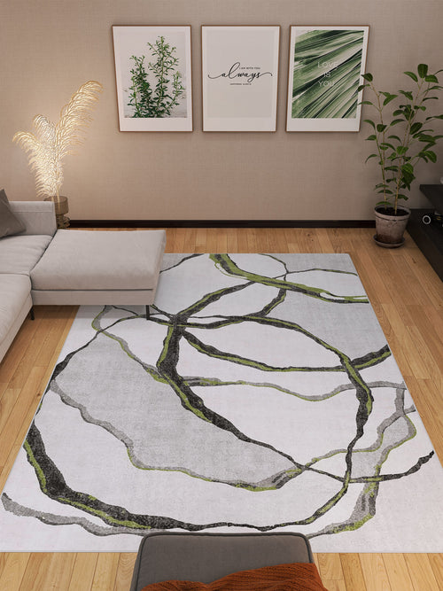 Bild 1 in Galerieansicht laden. A modern living room with a light gray sectional, potted plants, wooden flooring, three botanical prints, and the Tattered Grace - Washable Rug - JRN49 featuring black and green abstract lines.