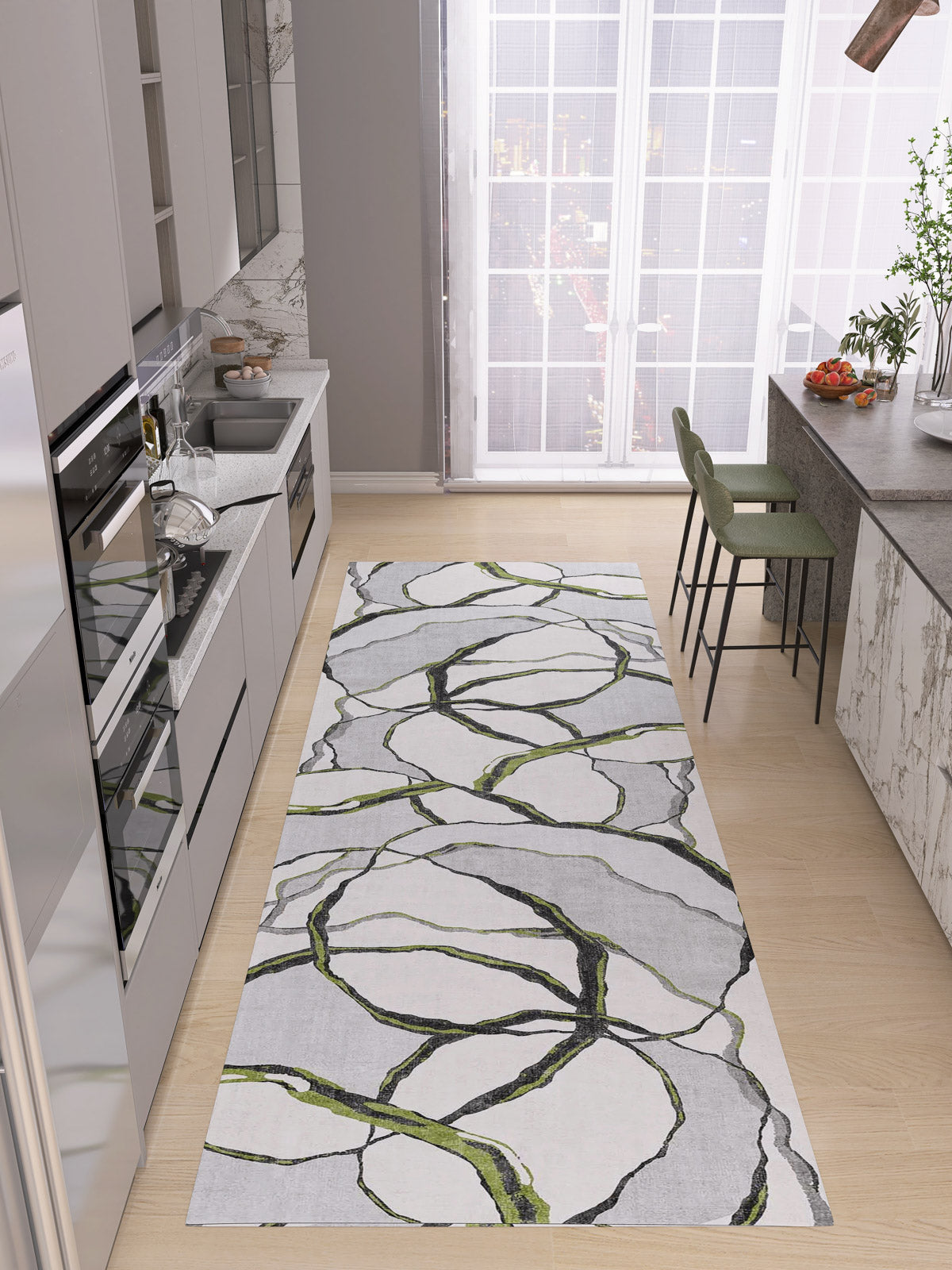 Modern kitchen with light wood floors, grey cabinets, built-in appliances, and a custom-size Tattered Grace - Washable Rug - JRN49 in white, grey, and green. Large windows brighten a breakfast bar with two green stools.