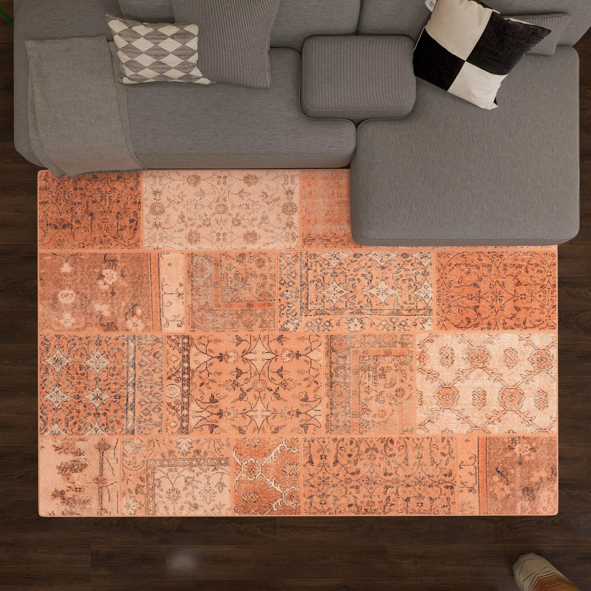 A Terracotta Patch - Washable Rug - JRN1037 (Custom Size) lies on a dark wood floor in front of a gray sectional sofa with two patterned throw pillows.