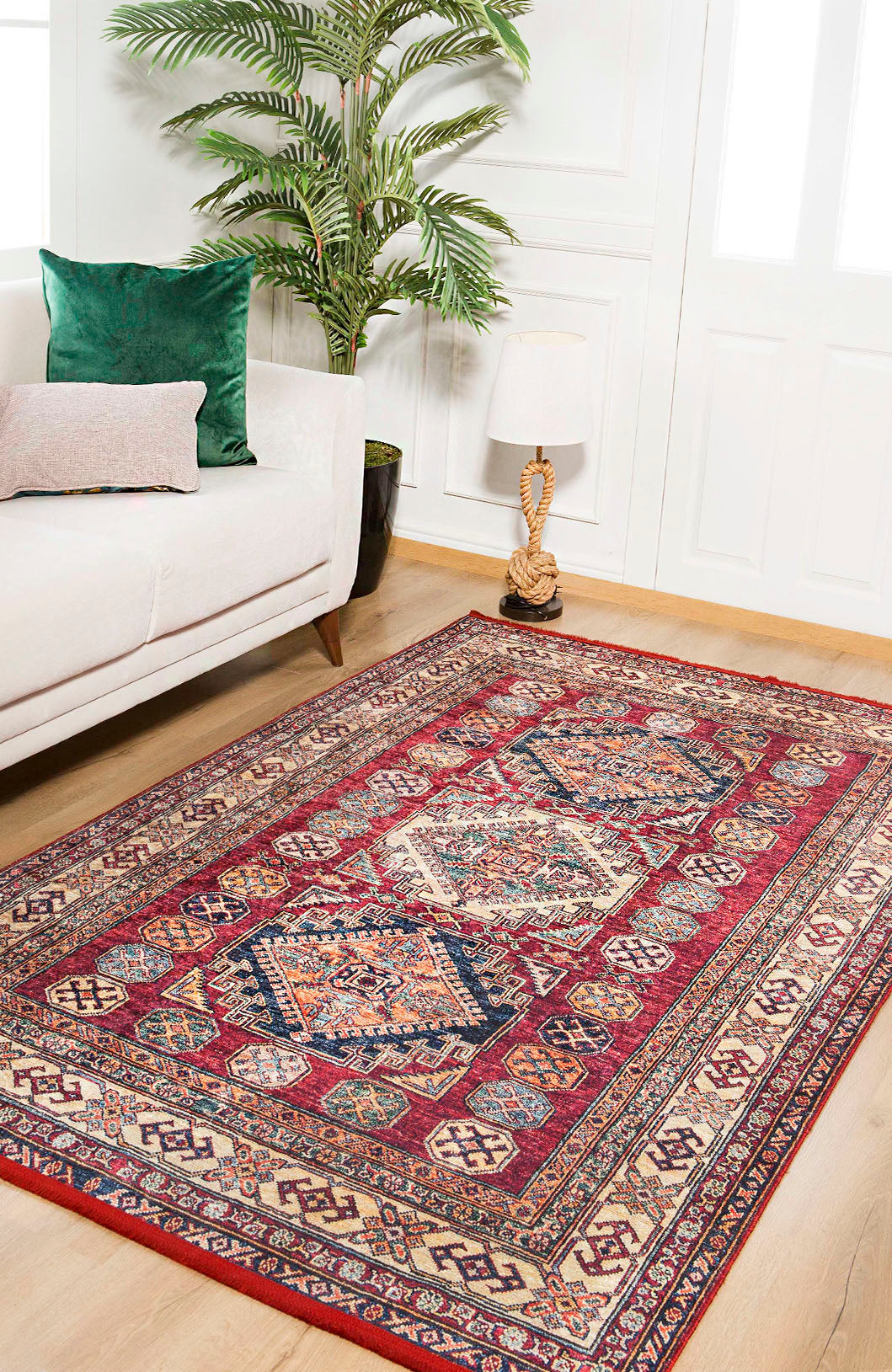 A living room with a white sofa, green and pink cushions, a plant, a lamp on a side table, and the Time-Honored Textures - Washable Rug - JR40 (Custom Size) with geometric designs—perfect for high-traffic wooden floors.