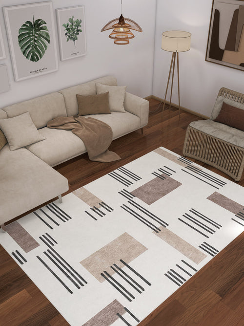 Load image 1 in gallery view. A modern living room with a beige sectional, wicker chair, and abstract art features the Timeless Scroll - Washable Rug - JRN45 (Custom Size), showcasing brown and black geometric patterns—perfect for high-traffic wooden floors.