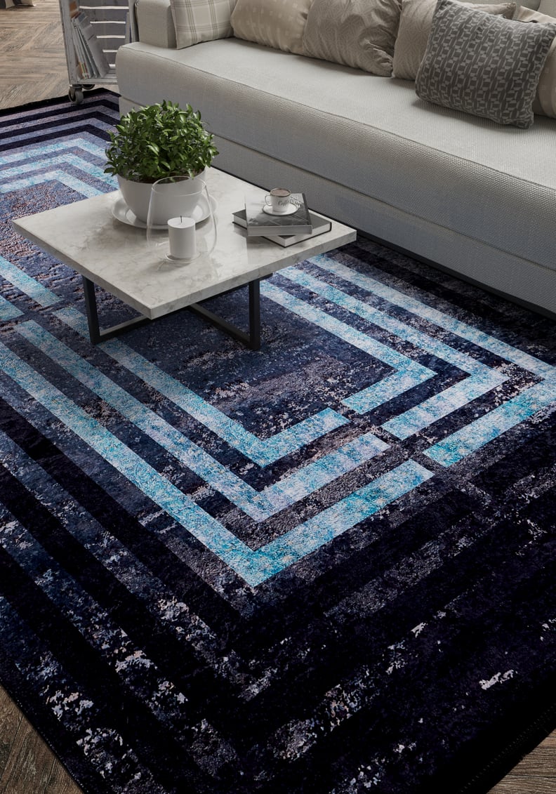 A modern living room with a white sofa, gray and plaid pillows, a marble coffee table with a plant and tray, and the Traditional and Timeless - Washable Rug - JR1408 (Custom Size) featuring dark blue geometric patterns.