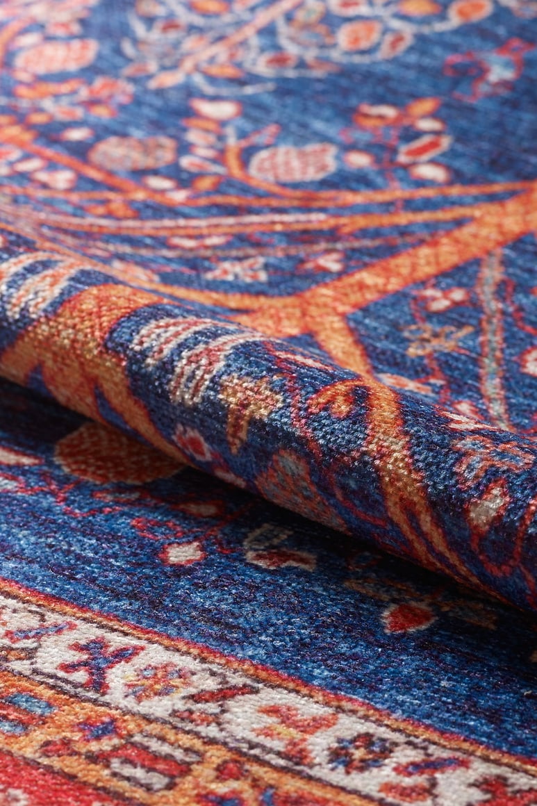 A close-up of the Tree of Plenty Red Blue Washable Rug - LCC3031, showcasing its intricate floral and geometric patterns in rich hues. Its detailed woven texture suits high-traffic areas and is ideal for allergy-sensitive households.