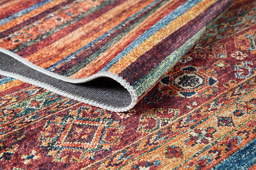 Load image 1 in gallery view. A close-up of the Tropic Thunder - Washable Rug - JR5077 (Custom Size), featuring vibrant geometric and floral patterns in red, orange, blue, and green. One corner is folded to reveal its textured, allergy-friendly underside.