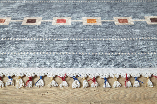 Load image 1 in gallery view. A close-up of the Tuscan Villa - Washable Rug - JR5058 (Custom Size) in blue, featuring textured fabric, a row of colored edge squares, and white tassels with red and blue accents—perfect for high-traffic spaces on a wooden floor.
