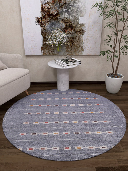 Load image 1 in gallery view. A cozy modern living room featuring the Tuscan Villa - Washable Rug - JR5058 (Custom Size) in round gray-anthracite, paired with a small white sofa, circular side table with books and flowers, tall potted plant, and abstract wall art—ideal for busy spaces.
