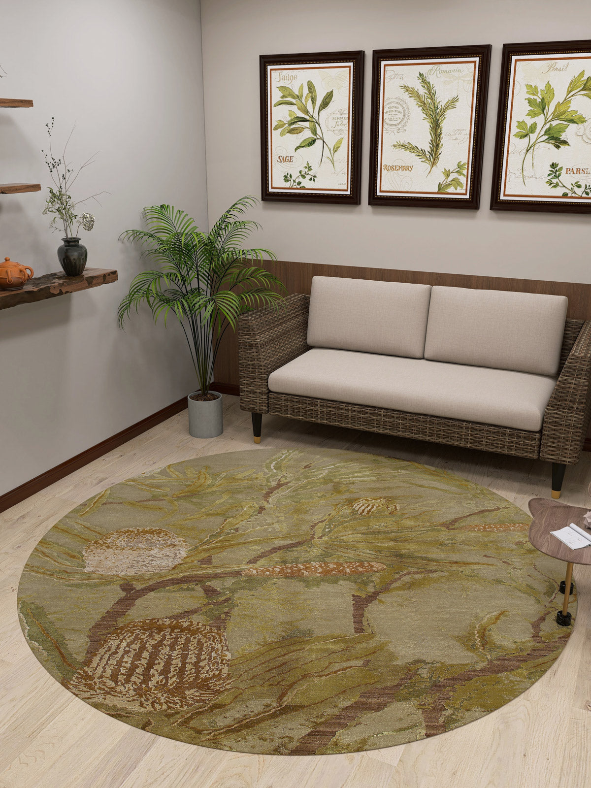 A cozy room features a beige wicker sofa, potted plant, wooden shelves with decor, framed botanical prints, and the Dreamweaver's Loom - Washable Rug - JRS001 in green and beige with a round flat weave pattern.