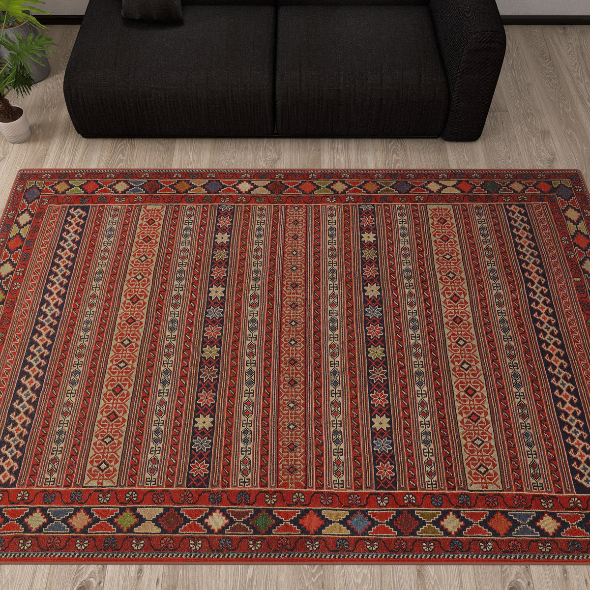 Red, blue, and beige striped rug with intricate geometric patterns, styled in a living room with a black sofa.