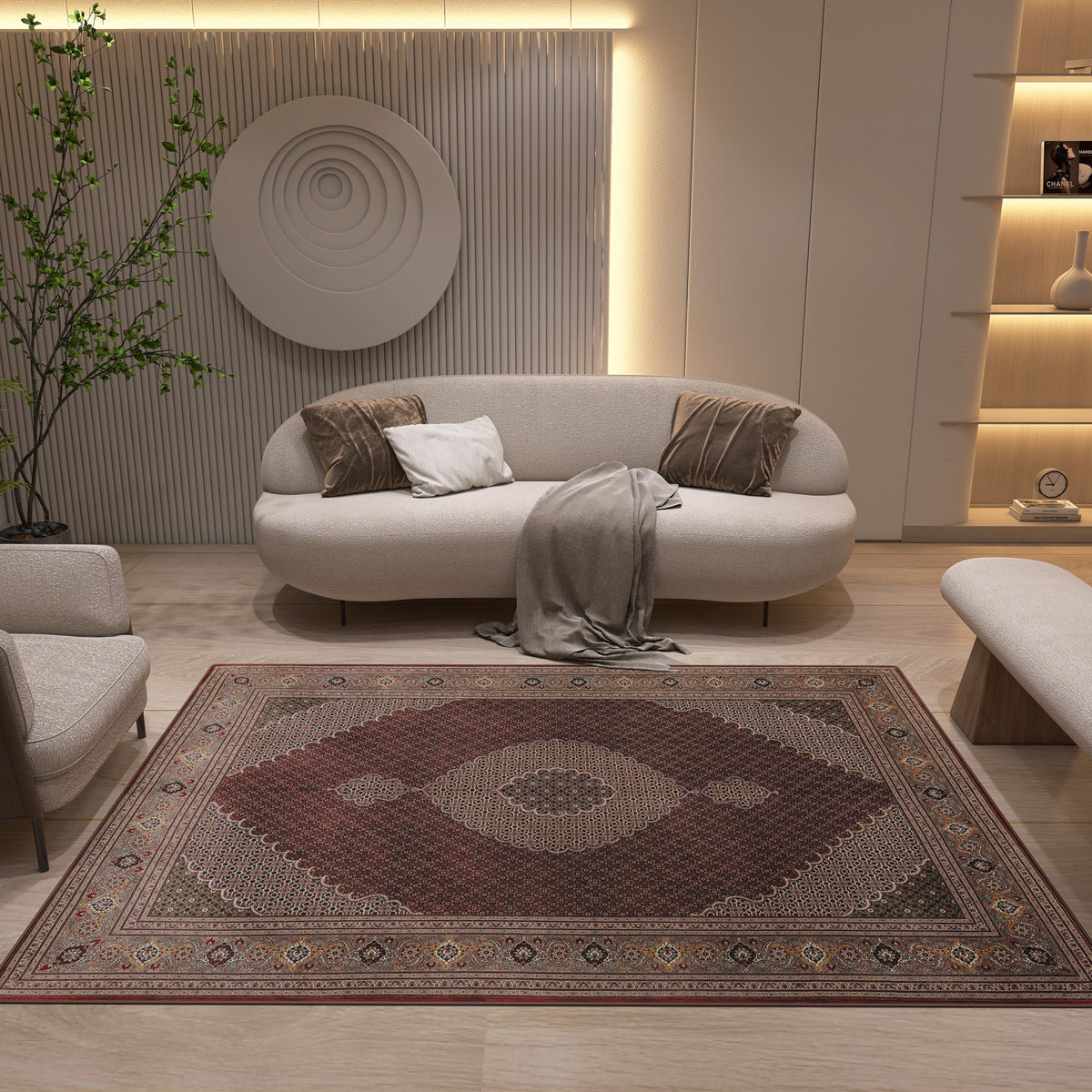 A modern living room features neutral furniture—a curved sofa, armchair, and bench—anchored by the Elysian Weave - Washable Rug - JRN1001 in red. Wall art, minimalist shelves, and a tall plant add cozy elegance to the space.