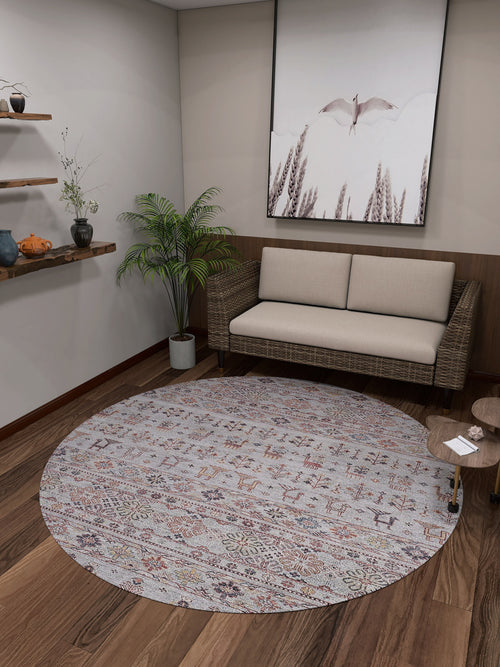 Load image 1 in gallery view. A cozy room with a wicker sofa, beige cushions, and the Nomad's Nest - Washable Rug - JR5088—ideal for high-traffic areas—plus a small wooden table, potted plant, wall shelves with decor, and large bird-themed artwork.