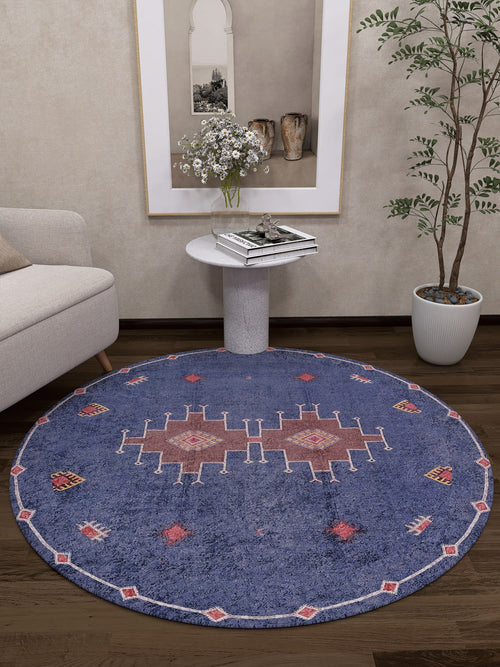 Load image 1 in gallery view. A modern living room with a Wanderer's Way - Washable Rug - JR5101 (Custom Size), a light sofa, white circular side table with flowers, tall potted plant, and decorative accents—perfect for high-traffic spaces.
