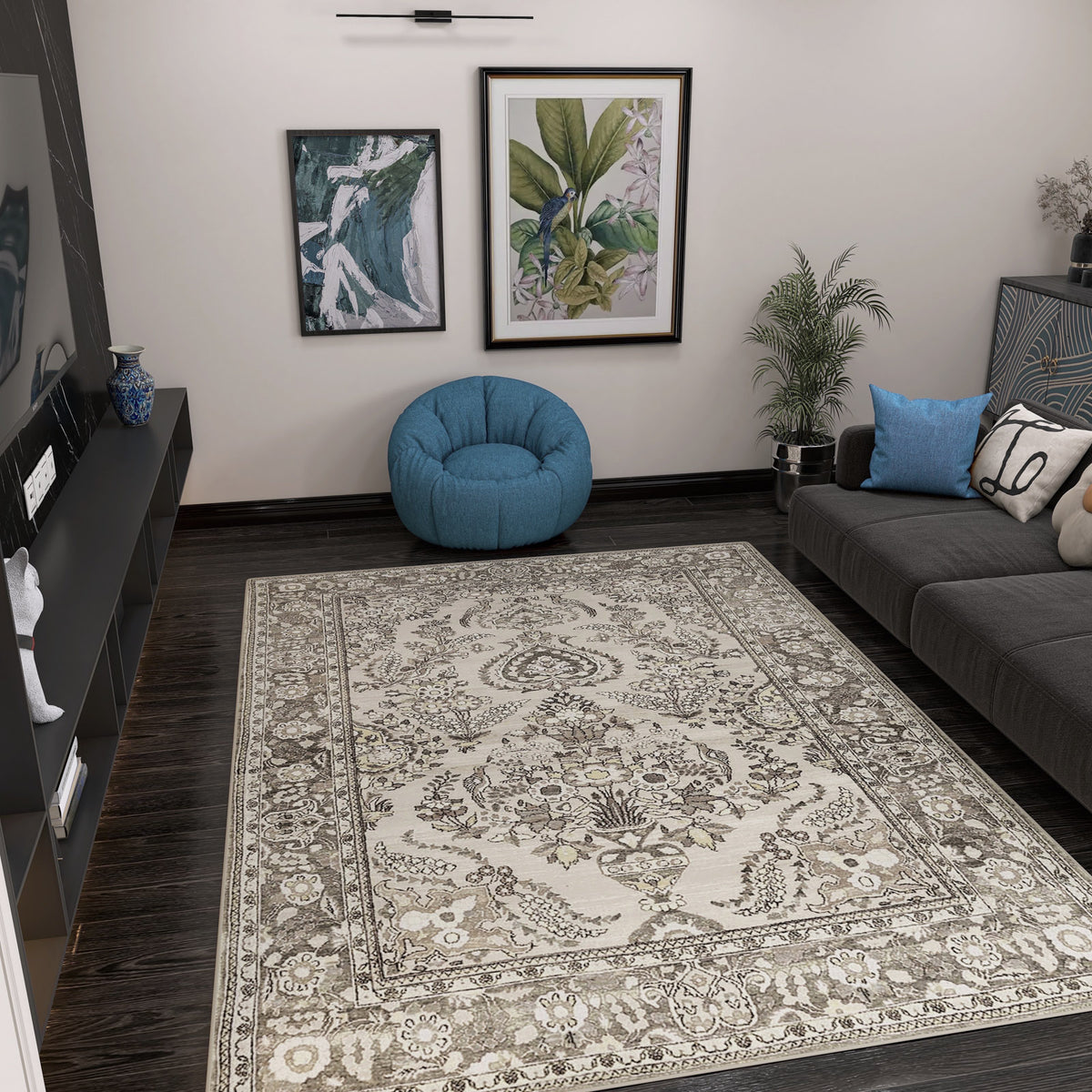 A living room with the Velvet Mosaic - Washable Rug - JRN1004 (Custom Size), dark wood floors, a gray sofa with blue and white pillows, a blue bean bag chair, houseplants, wall art, and a black shelf with decor and a TV.