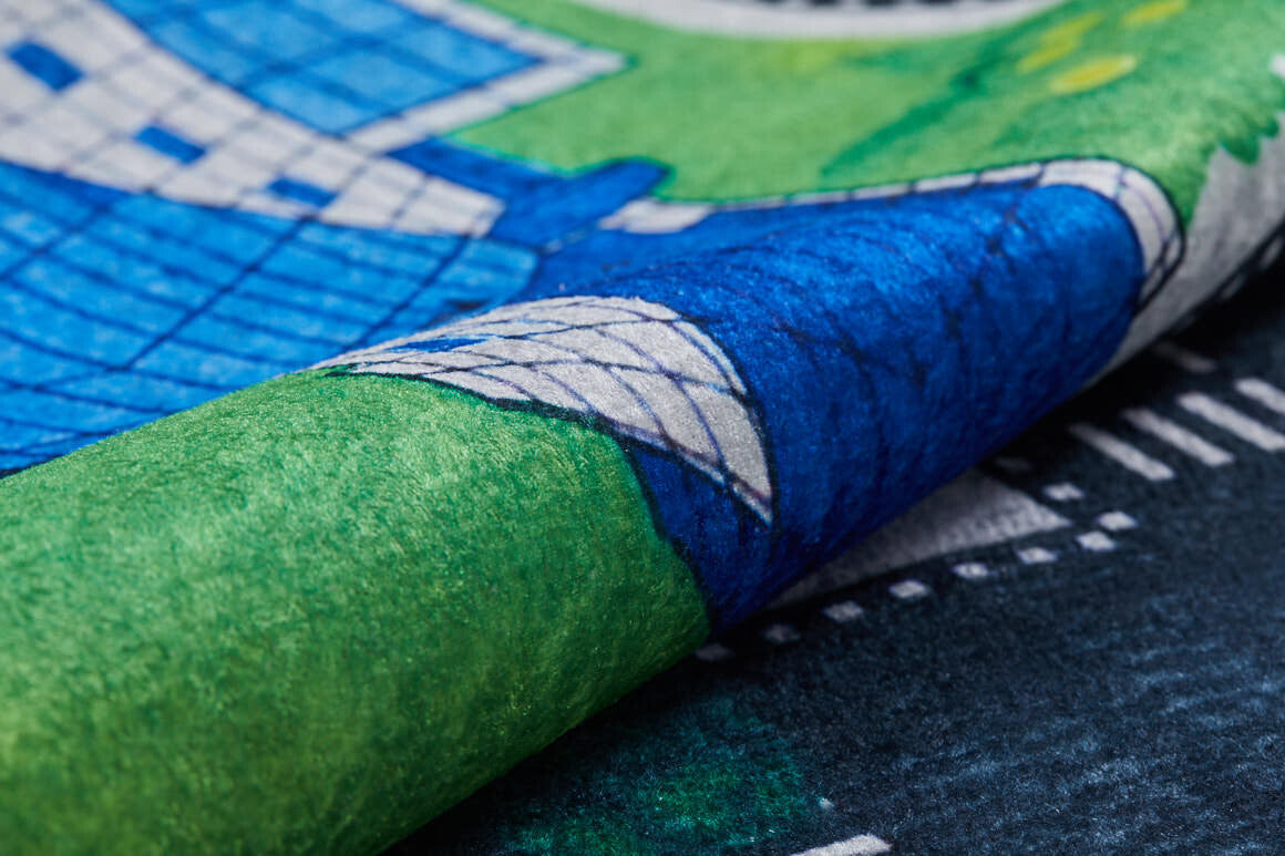 A close-up of the Urban Road - Machine-Washable Rug JRC013 (Custom Size), showcasing green, blue, and white patterns—suggestive of city roads—with a lifted corner for texture; ideal for high-traffic areas.