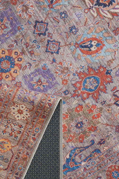 Bild 1 in Galerieansicht laden. The Velorio Floral Washable Rug - LCC3006 features intricate floral and geometric patterns in red, blue, orange, and purple. A folded corner reveals its textured dark backing, making it ideal for high-traffic areas.