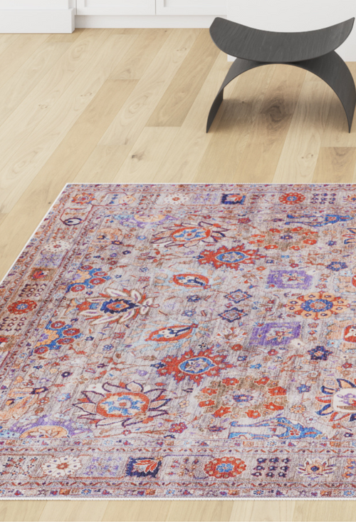 Load image 1 in gallery view. The Velorio Floral Washable Rug - LCC3006 (Custom Size), featuring intricate red, blue, and purple patterns, lies on a light wooden floor near a modern black curved stool—ideal for allergy-sensitive or high-traffic bright rooms.
