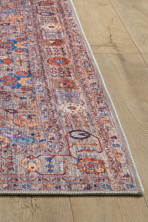 Load image 1 in gallery view. A close-up of the Velorio Floral Washable Rug - LCC3006 (Custom Size) showcases its intricate red, blue, and orange vintage-style design with a fringed edge, placed on light wood flooring—perfect for high-traffic areas in your home.
