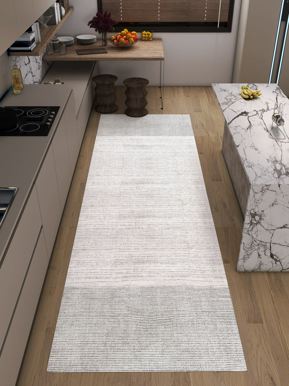 A modern kitchen with light wood floors, beige cabinets, a marble island, two wooden stools by a window-side table, a fruit bowl, and the Velvet Echo - Washable Rug - JRN25 (Custom Size), perfect for high-traffic areas.