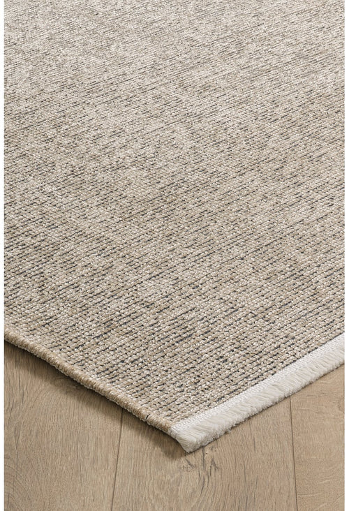 Bild 1 in Galerieansicht laden. A close-up of the Velvet Touch Beige Area Rug - PST002 shows its rectangular, textured surface with a subtle woven pattern. Placed on a light wood floor, this contemporary rug features a slightly raised edge with a white border on one side.