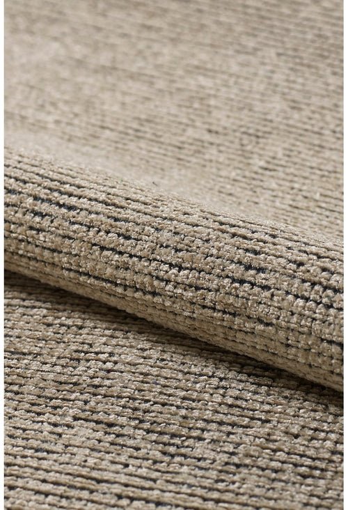 Bild 1 in Galerieansicht laden. Close-up of the Velvet Touch Beige Area Rug - PST002, featuring a textured beige surface with subtle dark speckles and a soft fold that highlights its contemporary style.