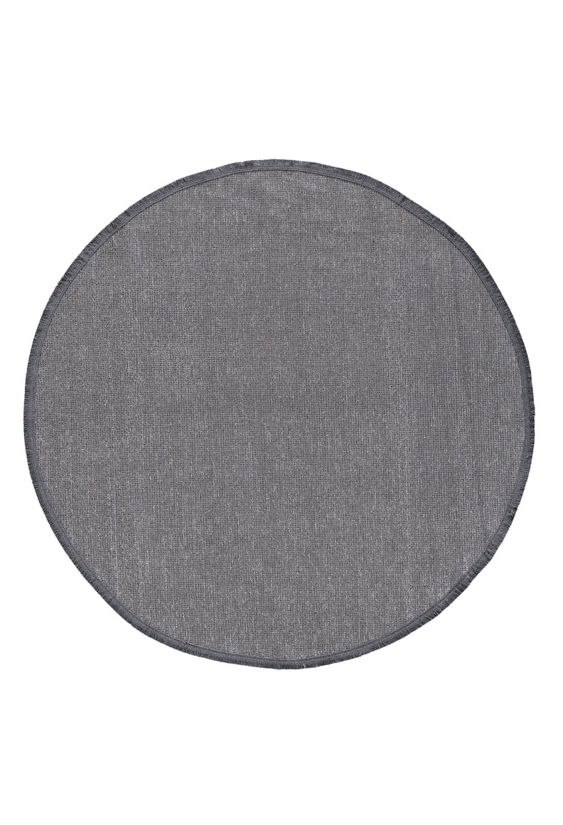The Velvet Touch Dark Gray Area Rug - PST004 features a round, flat shape with a subtly textured, dark gray surface and stitched edges—ideal for minimalist decor lovers. Shown on a white background.