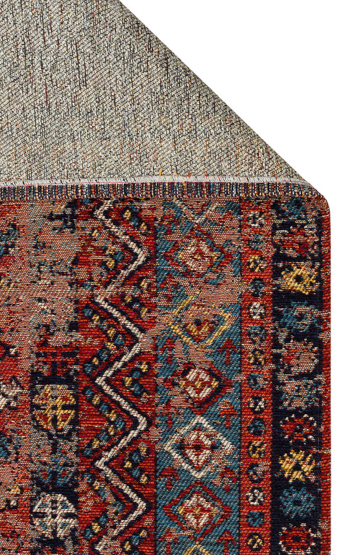 Load image 1 in gallery view. The Vintage Echo - Washable Kilims - AND04 features colorful geometric patterns in red, blue, black, and yellow, with a folded corner that reveals its beige woven underside.