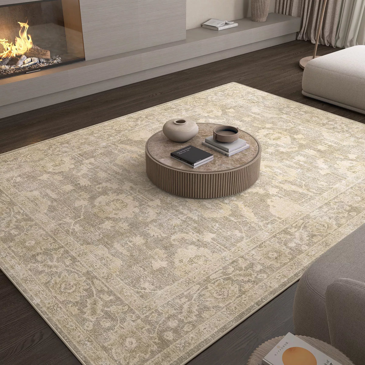 A living room featuring the Vintage Linen - Washable Rug - JRN1028, perfect for allergy-sensitive and high-traffic areas, with a round coffee table holding two vases and books, dark wood flooring, fireplace, and neutral-toned furniture.