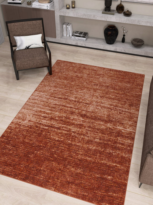 Load image 1 in gallery view. A modern living room featuring the Vintage Reverie - Washable Rug - JRN31 in deep red ombre design on light wood floors, placed near a brown chair with a white pillow and built-in shelves showcasing decor, books, and vases.