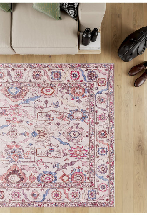 Load image 1 in gallery view. The Vivencia Authentic Washable Rug - LCC3016 (Outlet) US, featuring red, blue, and pink patterns, is displayed on a light wood floor next to a beige sofa, shoes, a bag, books, and two dark bottles.