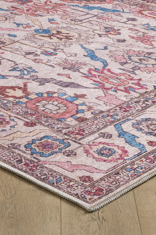 Load image 1 in gallery view. Corner of the Vivencia Authentic Washable Rug - LCC3016 (Outlet) US on a wooden floor, showcasing pink, blue, cream, and beige floral and geometric patterns with a decorative border and slightly distressed, vintage style. Durable and washable.