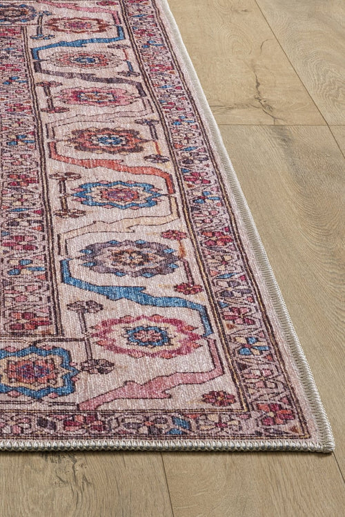 Load image 1 in gallery view. A close-up of the Vivencia Authentic Washable Rug - LCC3016 (Outlet) US in pink, blue, and cream with geometric and floral designs on a light wooden floor, showing the detailed border of this durable, washable rug.