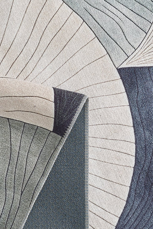 Bild 1 in Galerieansicht laden. A close-up of the Vivian Modern Washable Area Rug - MDJ010 shows abstract, curved shapes in cream, blue, and gray. One corner is folded to reveal its textured backing—perfect for high-traffic or allergy-sensitive homes.
