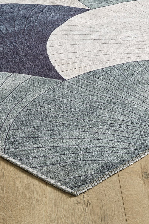Bild 1 in Galerieansicht laden. A close-up of the Vivian Modern Washable Area Rug - MDJ010, featuring curved, overlapping shapes in gray, blue, and cream on a light wooden floor. Visible detailed edge stitching makes it ideal for high-traffic and allergy-sensitive homes.