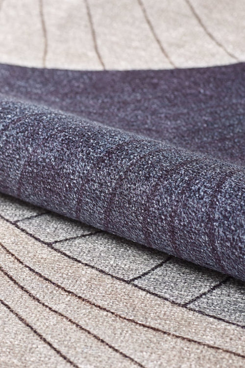 Load image 1 in gallery view. A close-up of the Vivian Modern Washable Area Rug - MDJ010 (Custom Size), rolled up to show its gray-anthracite base and geometric pattern in beige, gray, and dark purple with curved and straight lines for a modern, textured look.