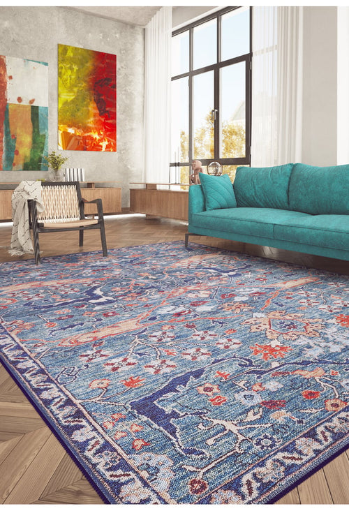 Load image 1 in gallery view. A modern living room with a teal sofa, wooden chair, and the Whisper Authentic Blue Washable Rug - LCC3034 (Custom Size), ideal for high-traffic areas. Abstract art, large windows, and wood floors create a bright, cozy atmosphere.