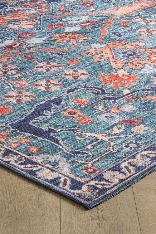 Load image 1 in gallery view. A close-up of the Whisper Authentic Blue Washable Rug - LCC3034 (Custom Size) featuring vibrant orange and cream floral patterns with a decorative border, shown on a light wooden floor—ideal for high-traffic areas.