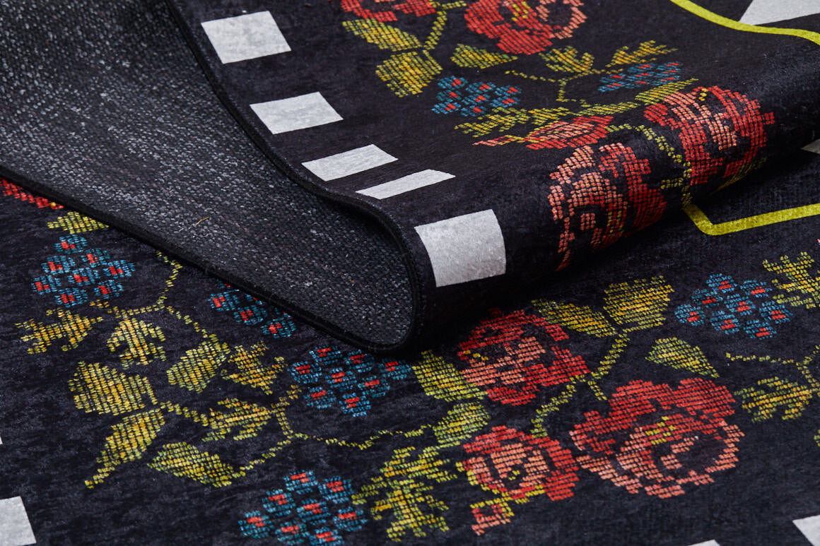 A close-up of the Wildflower Wonderland - Washable Rug - JR587 (Custom Size) shows a folded black corner with a floral pattern in red, pink, and blue flowers, green leaves, and white rectangles—perfect for high-traffic areas.